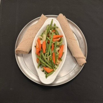 Ethiopian Fossolia dish made with sautéed green beans, carrots, and onions, cooked in traditional spices and served on injera.