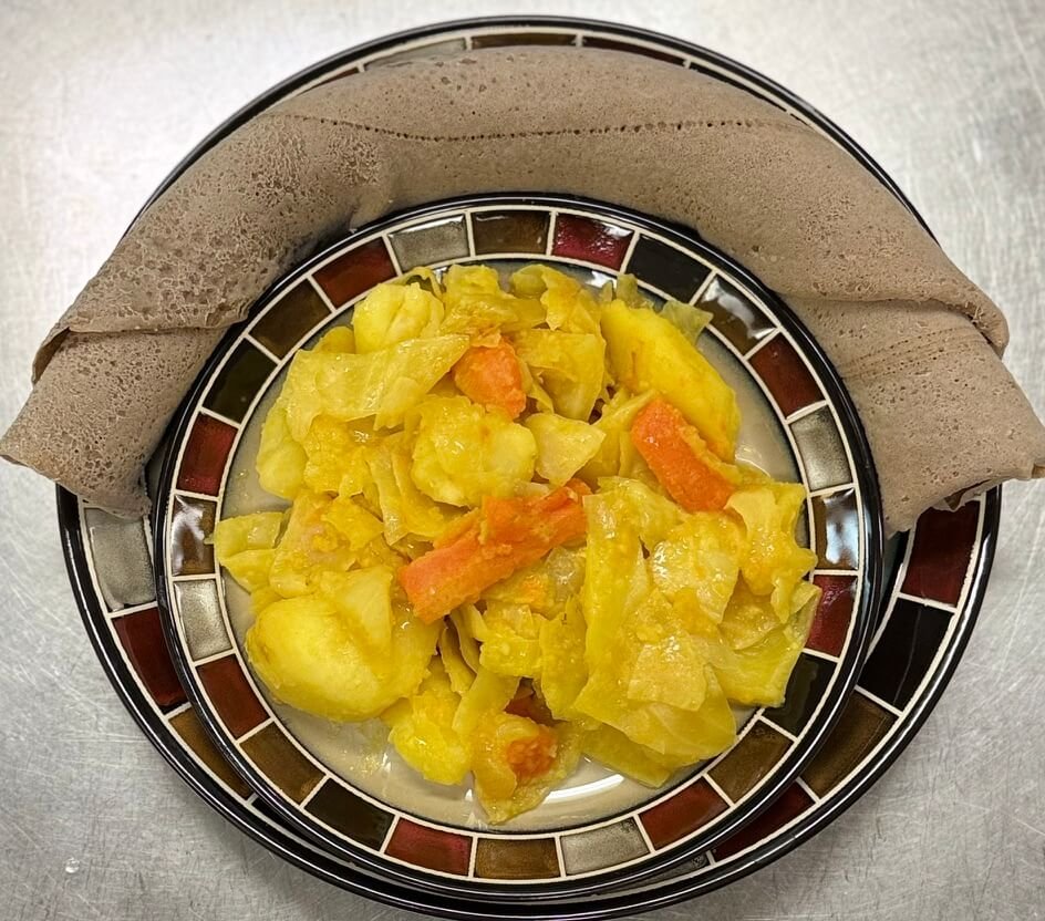 Ethiopian Tikil Gomen—sautéed cabbage, carrots, and potatoes cooked with garlic, onions, and turmeric, served with injera as a mild and comforting veggie dish.